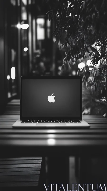 Laptop with illuminated logo sits centered on outdoor table