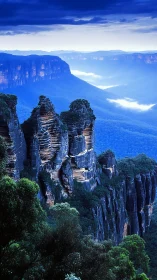 Layered sandstone cliffs above forested valley at dusk.