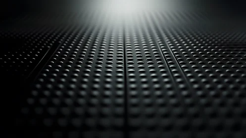 Abstract close-up of black perforated metal surface with dramatic lighting.