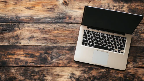 Cozy laptop workspace on a rustic wooden desktop surface.