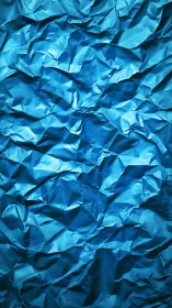 Crumpled metallic blue foil surface with random folds.
