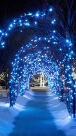 Snow-covered pathway under blue LED light tunnel at night.