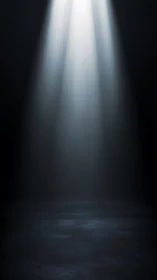 Lonely stage spotlight cuts through deep surrounding darkness.