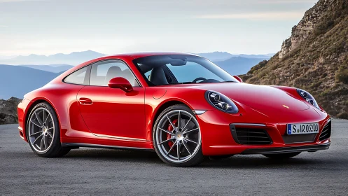 Aerodynamic red coupe framed by mountainous coastal roadscape.