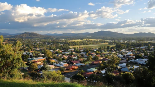 Sunlit country town cradled by rolling blue-green ranges.