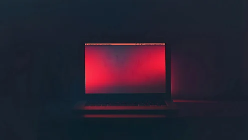 Laptop screen displays red gradient in low ambient light