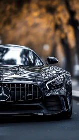 Sleek black Mercedes front glows against autumn bokeh street.