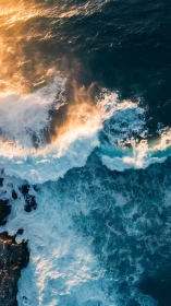 Sunlit breakers collide with deep teal sea in soaring view