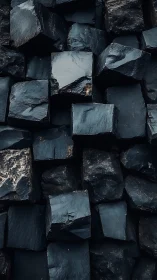 Stacked dark stone cubes with rough glossy textures.
