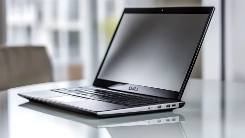 Dell ultrabook laptop on glass desk in modern office.
