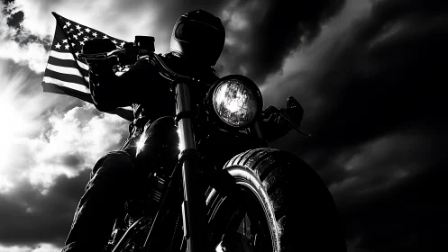 Motorcyclist holding US flag against dramatic cloudy sky.