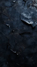 Fractured dark slate surface reveals layered metallic substrata