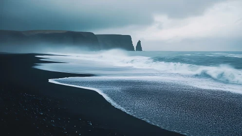 Moody black sand shoreline welcomes rolling misty waves gently