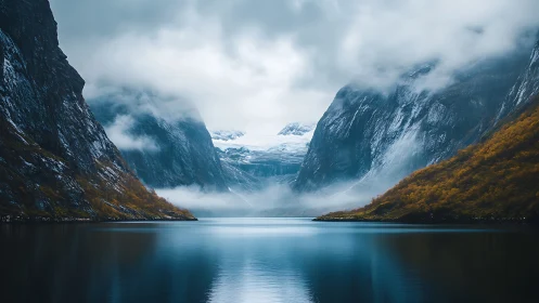 Mountain fjord with calm water and low cloud cover.