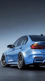 Rear three-quarter view of blue sports sedan on smooth asphalt.