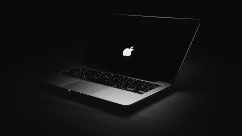 Open laptop glows in dramatic low key lighting against darkness