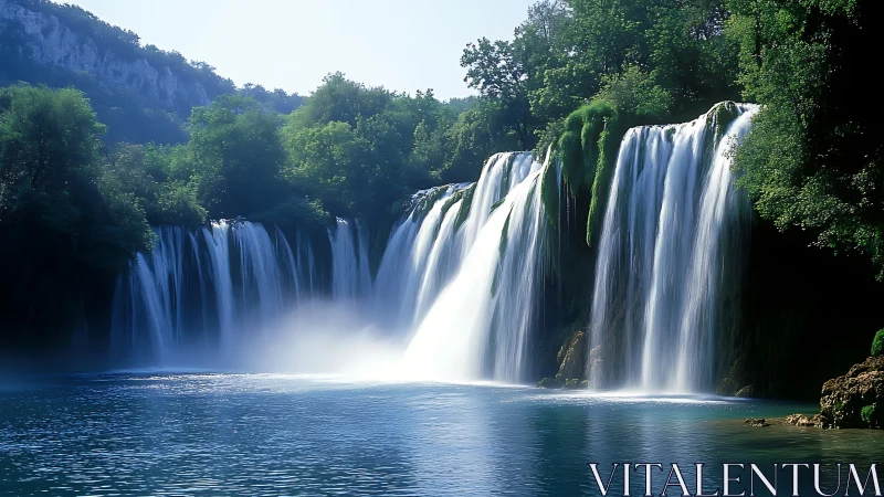 Wide cascading waterfalls over forested river cliffs.