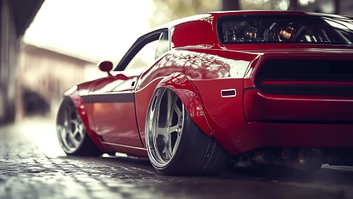 Low-slung red muscle car with widebody stance on street.