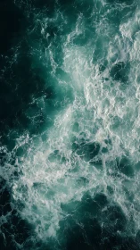 Storm-tossed teal ocean surface churns with foaming waves