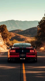 Red sports coupe aligns with mountain road under warm sunset light