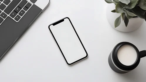 Minimal workspace with smartphone, laptop, plant, coffee mug.