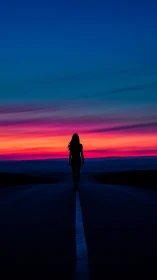 Silhouetted figure on vanishing highway at high-chroma sunset.