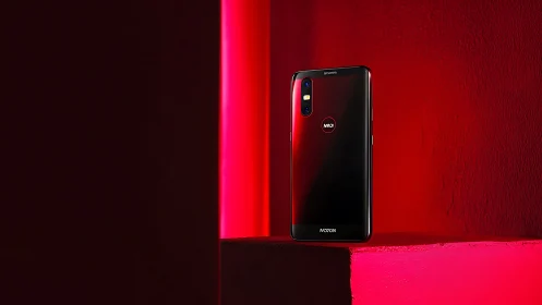 Black smartphone on red pedestal in bold studio lighting.