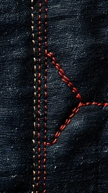 Macro view isolates denim fabric seams and red stitching