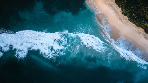 Aerial turquoise surf line curves along secluded shore.