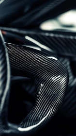 Curved carbon fiber detail in dramatic macro focus.