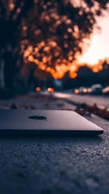 MacBook positioned on street at sunset with bokeh lights