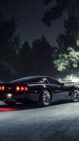 Black sports coupe glows under starlit forest highway night
