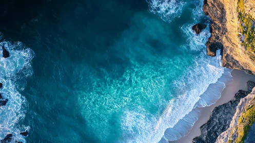Aerial view captures turquoise surf breaking against rugged cliff