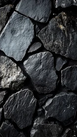 Dark irregular stone wall texture in close-up view.