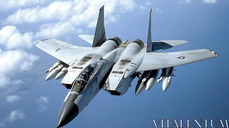 Modern fighter jet cruises above clouds in clear blue sky.