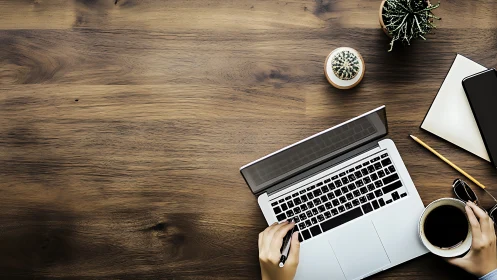 Overhead workspace with laptop, coffee mug, notebook, succulents