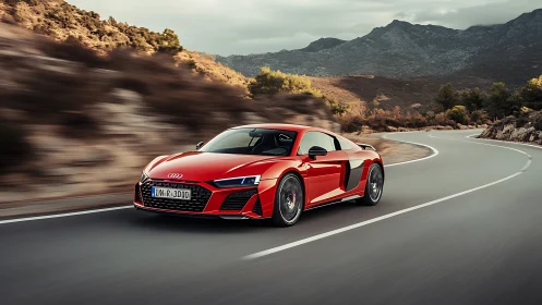 Red mid‑engine sports coupe negotiating mountain switchback road.
