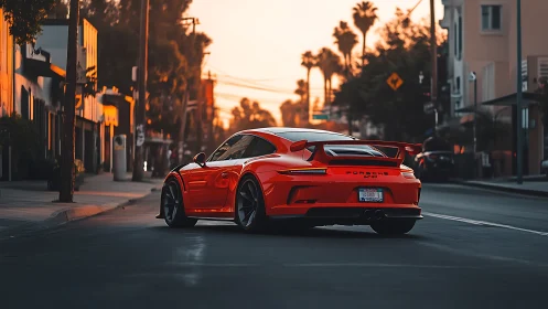Red Porsche sports car on city street at sunset time.