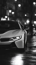White sports coupe cuts wet city street in moody monochrome.
