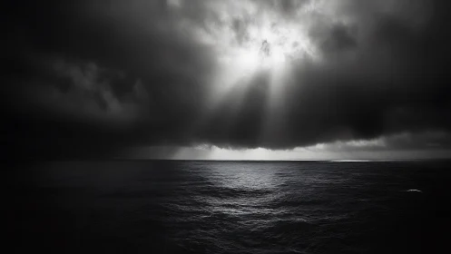 Monochrome seascape under dense storm clouds with sun rays.