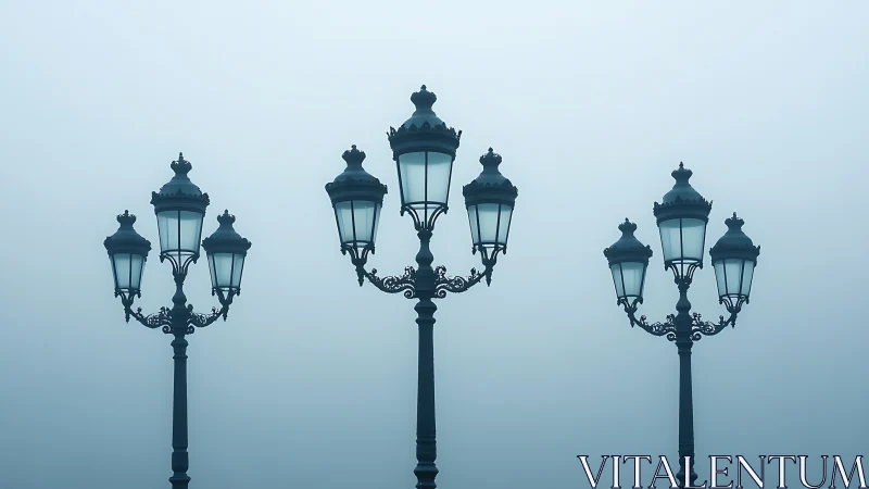 Foggy morning view of three ornate vintage lampposts.
