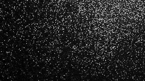 Silver glitter dust sparkles across deep black surface.