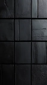 Matte black textured square tile wall surface closeup.