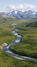 River ribbon curls toward stoic, snowlit mountain guardians