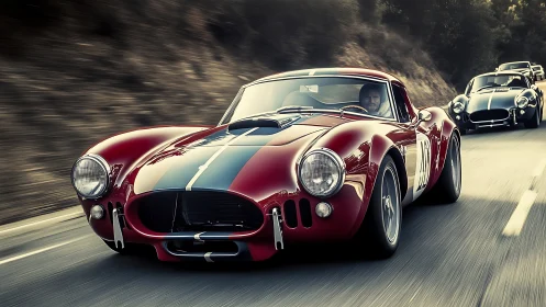 Scarlet vintage race cars storming a sunlit mountain road.