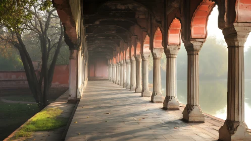 Sunlit Mughal arcade beside tranquil reflective waters.