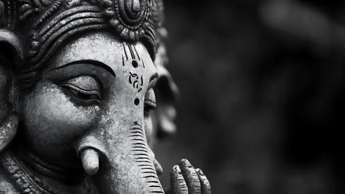 Monochrome close-up of weathered Ganesha stone sculpture.