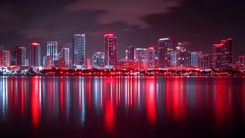 Neon scarlet skyline mirrored across calm harbor waters.