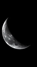 Crescent moon close-up with sharp craters in deep space.