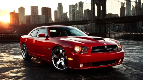 Red performance sedan is parked before urban bridge skyline